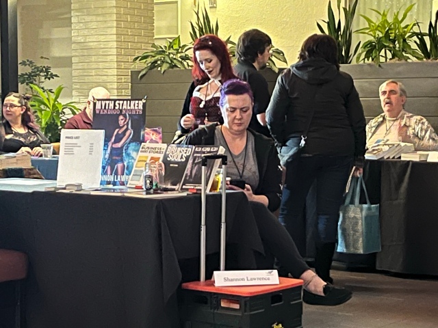 Shannon And I Took "Stalky" Photos of Each Other and Sent Them To Each Other. We Sat Kattycorner From Each Other. COSine 2024 Author Signing. (© 2024, F. P. Dorchak)